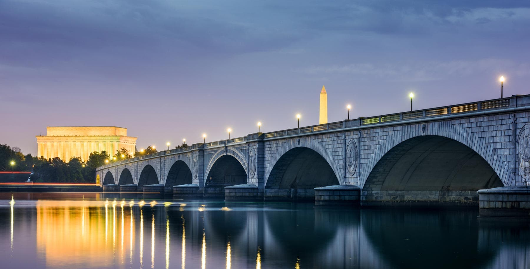 A bridge at night with the Washington Monument in the background