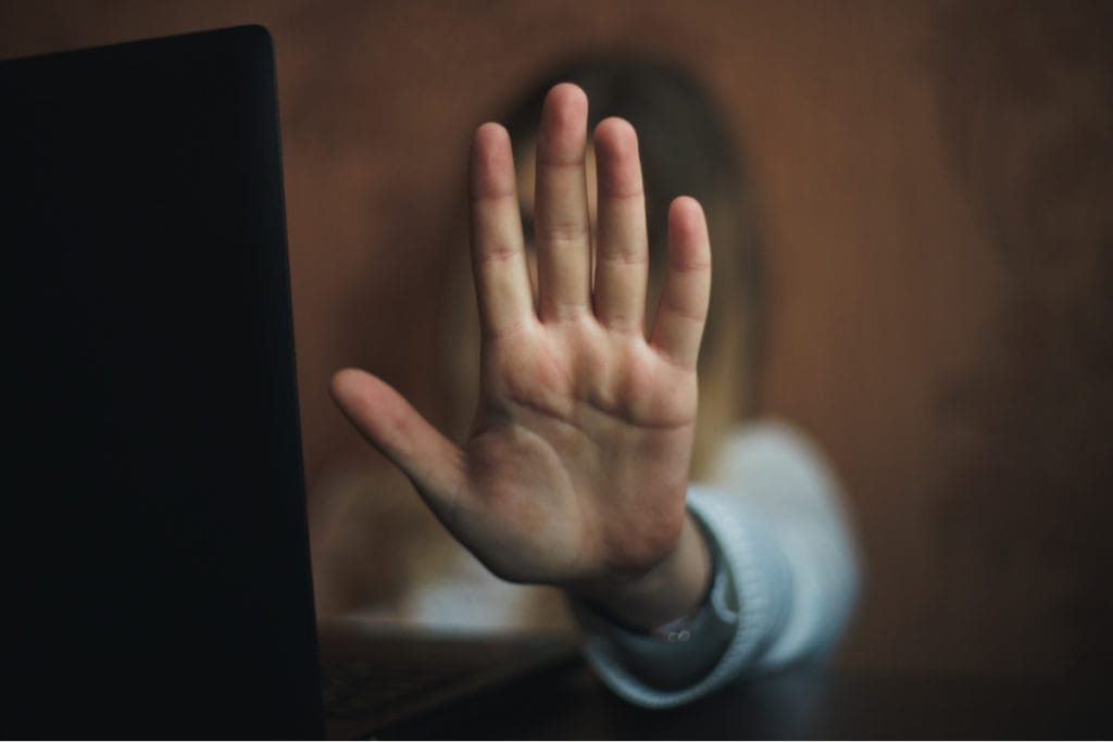 female on computer with hand up to show privacy and prevent harassment