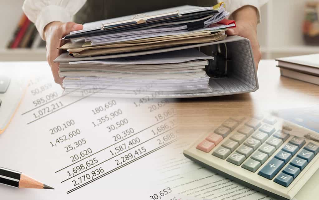 stack of papers inside binder next to a calculator