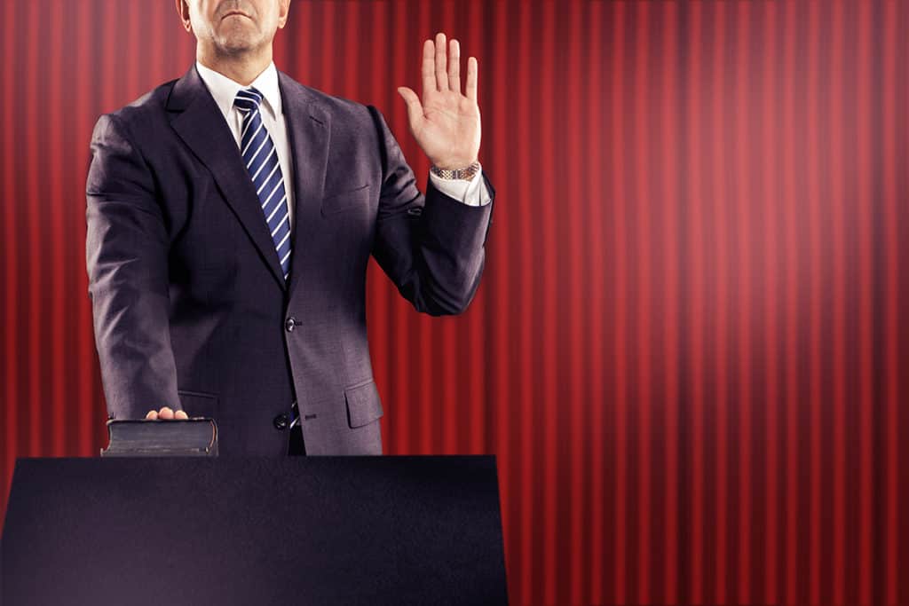 Person with hand on bible and hand raised giving oath, consumer testimony