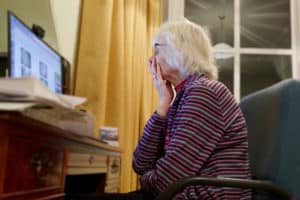 Woman looking at computer, social media scams against vulnerable groups