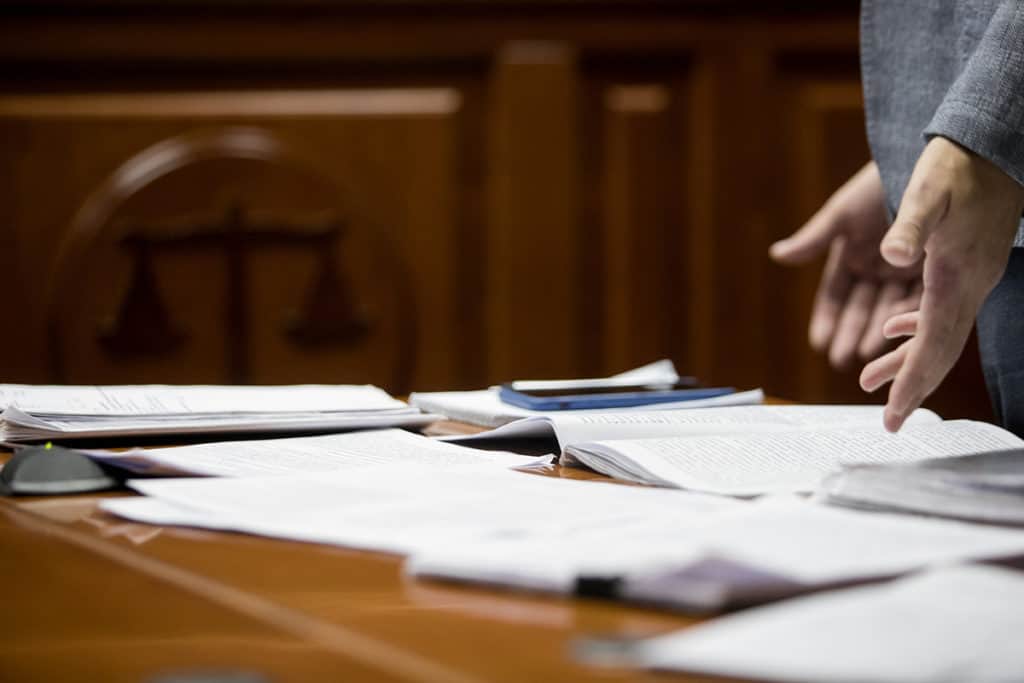 person standing next to a table with a pile of papers