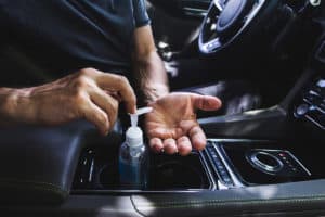 man using hand sanitizer in vehicle